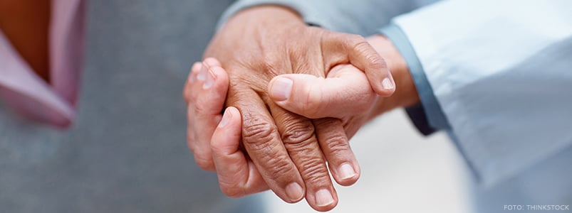 Vårdpersonal håller i äldre patients hand
