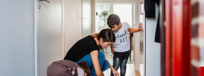 Mamma som hj&auml;lper sina barn p&aring; med skorna