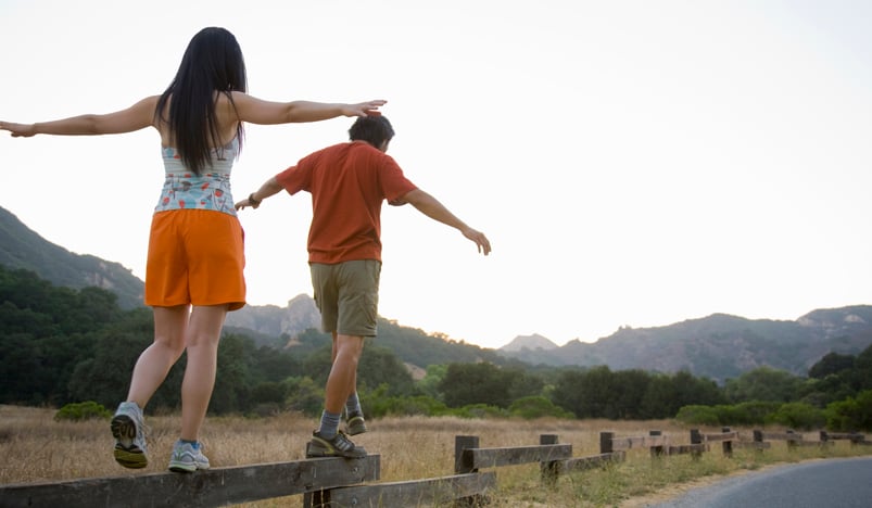 Kvinna och man balanserar på staket