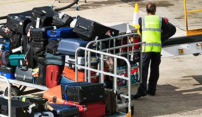 Person lyfter resväskor på ett transportband på flygplats