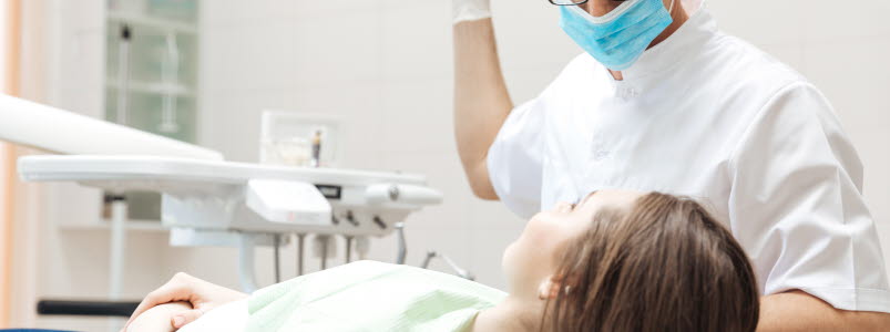 Tandläkare som ska undersöka en ung kvinna
