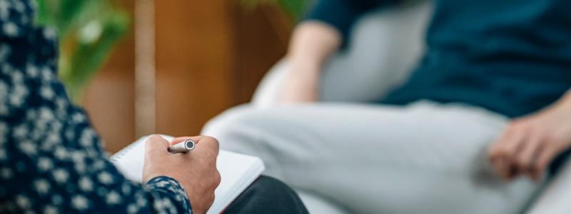 Person taking notes listening to another person