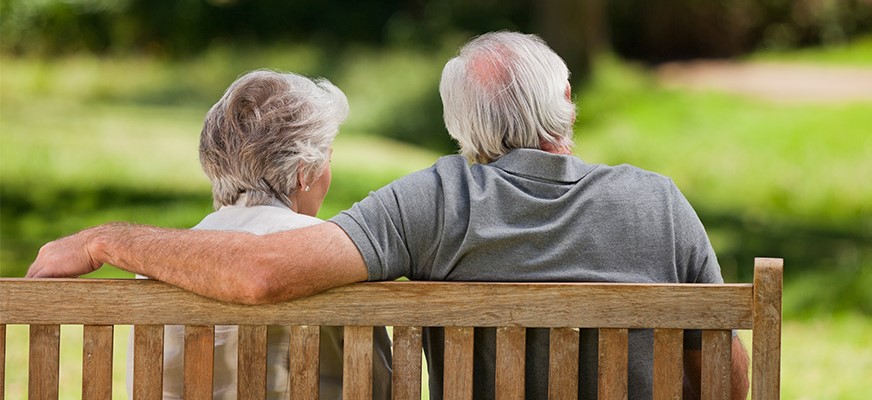 Äldre par sitter på parkbänk