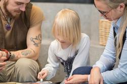 5-årig flicka ritar med krita på bord medan pappa och socialsekreterare tittar på