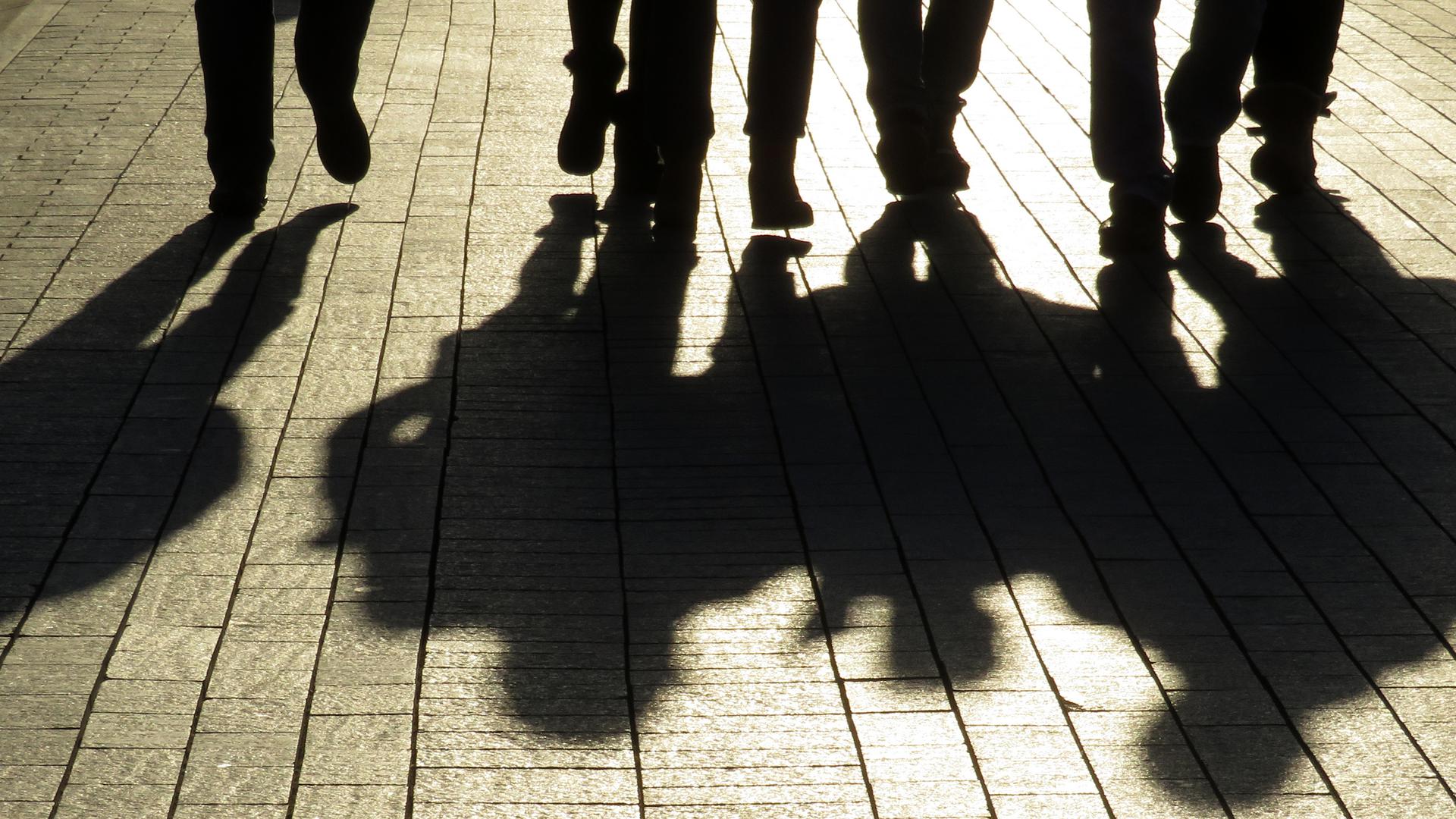 Silhuetter och skuggor av människor på gatan. Publiken går ner på trottoaren, begreppet främlingar, brott, maffian, samhället, gatugäng