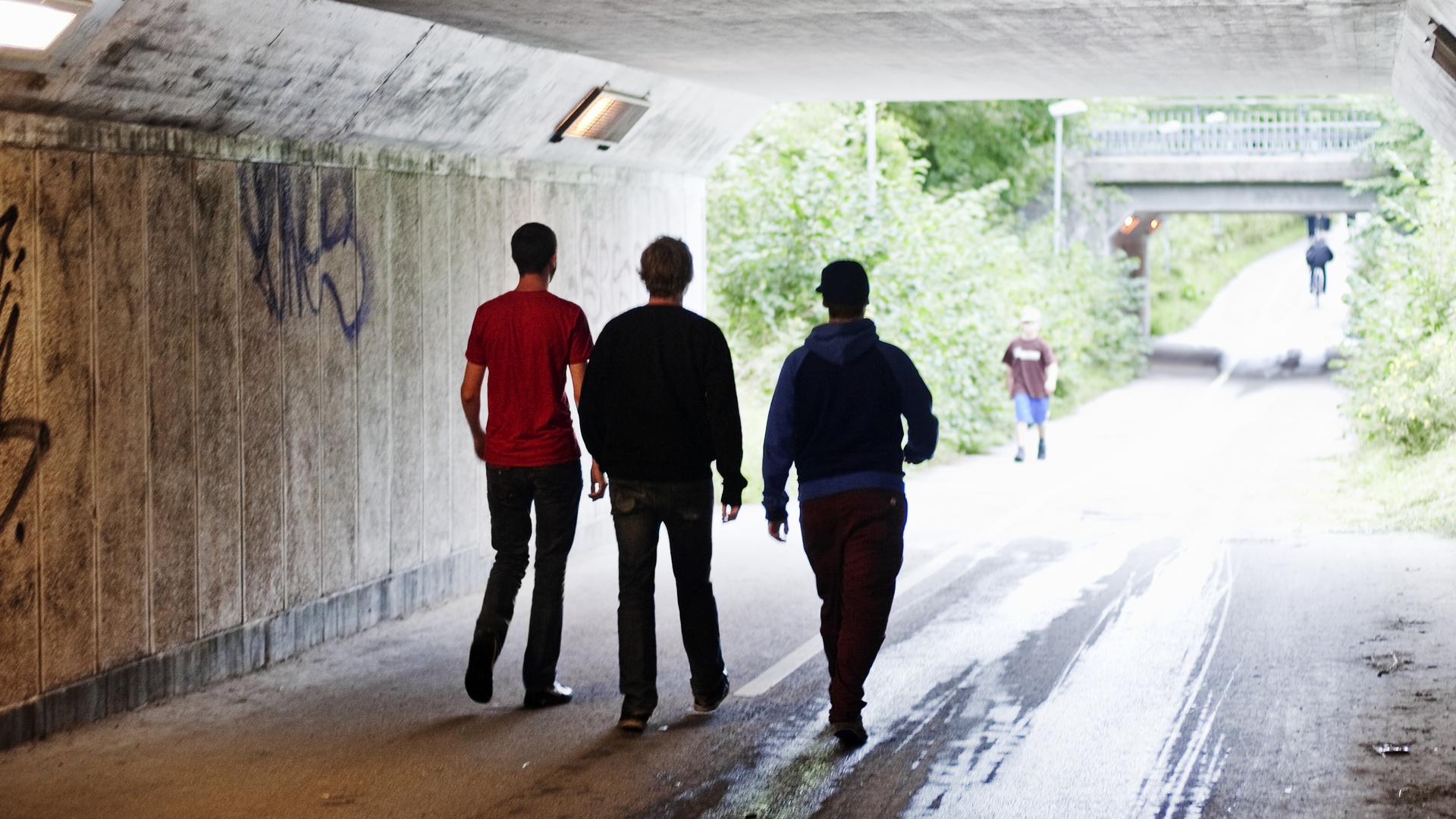 Tre unga killar går i gångtunnel
