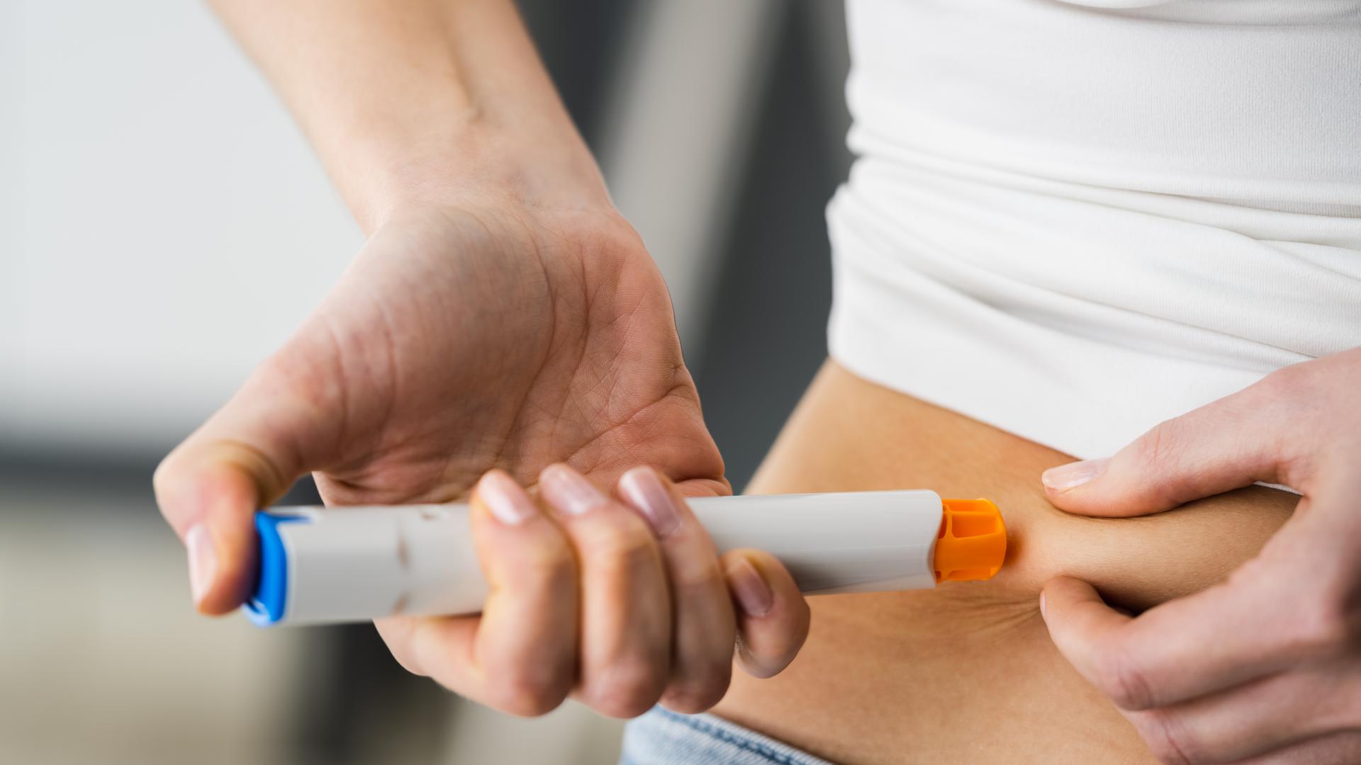 Medicament Self Injection In Belly Using Syringe With DrugKvinna som ger sig själv en injektion i magen med en injektionspenna