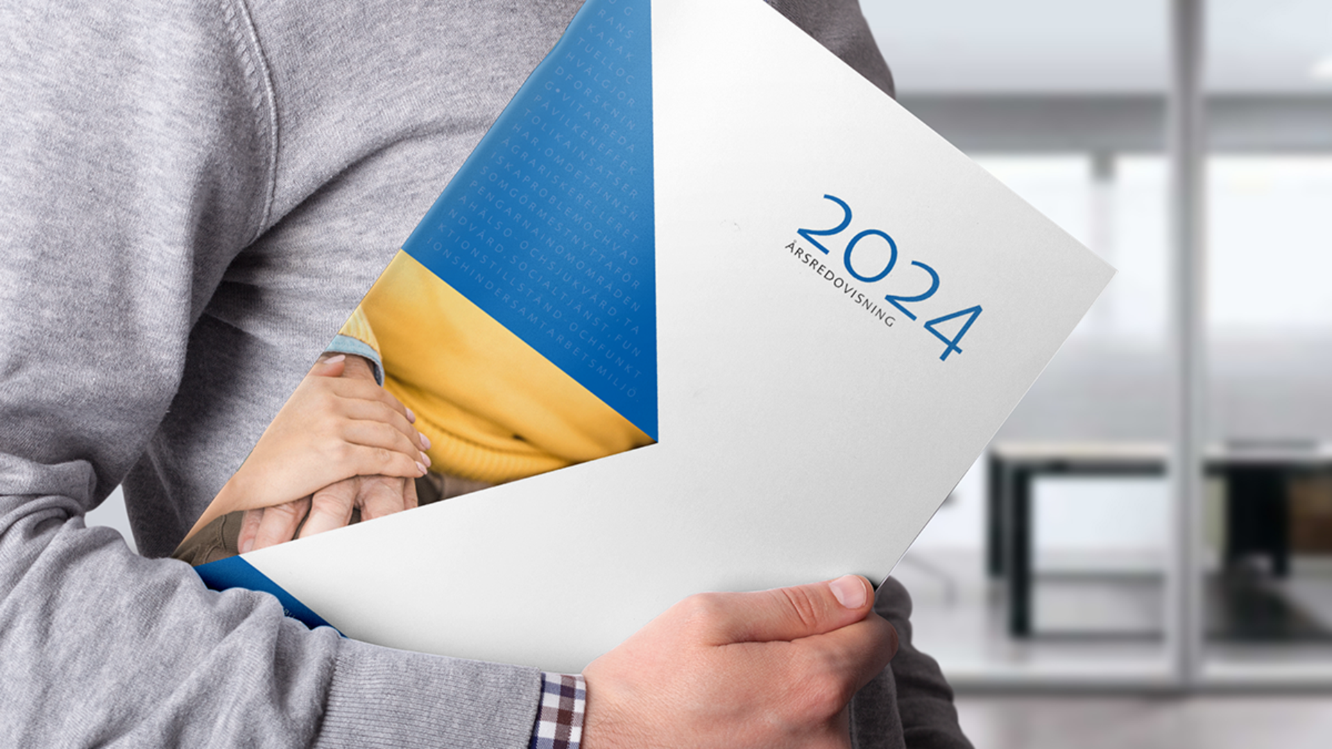 Man som håller SBU:s årsredovisning 2024 under armen.