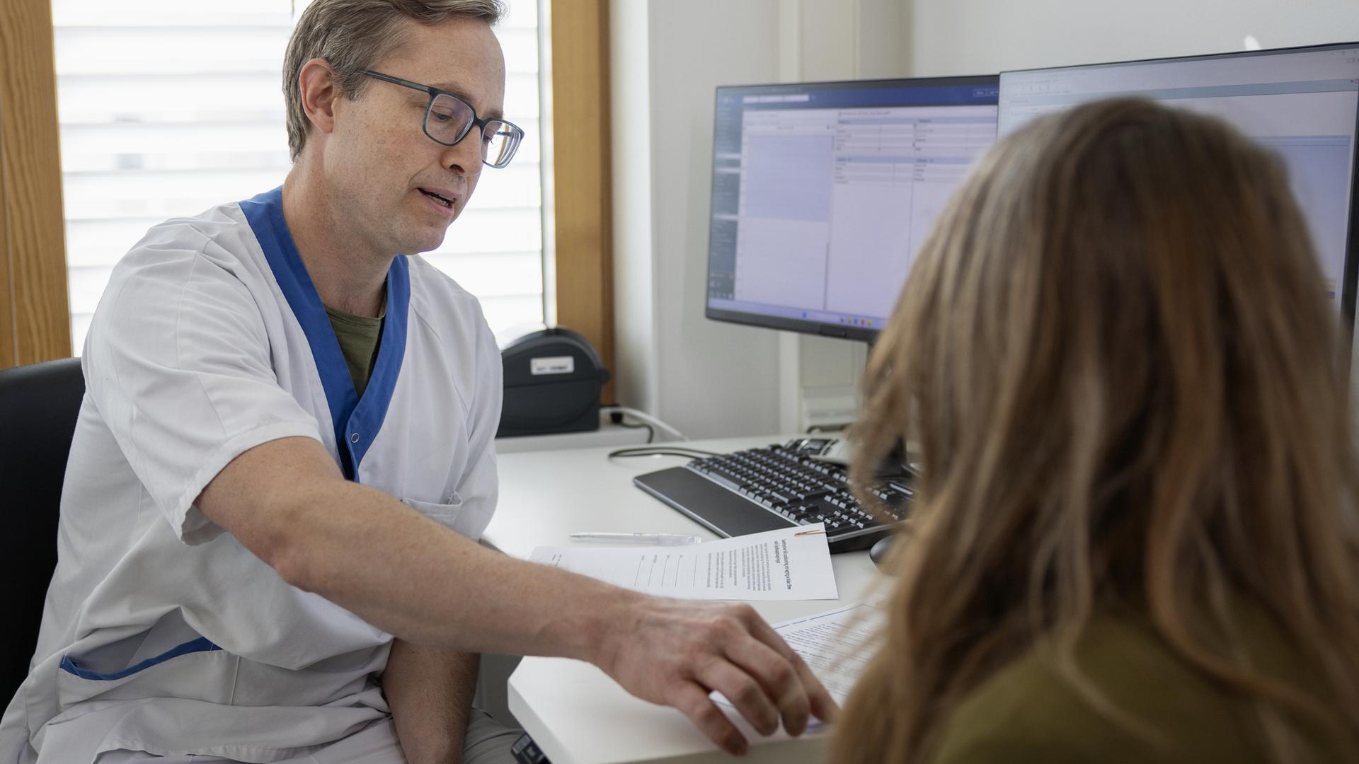 Sjukvårdspersonal i samtal med patient på sjukhus i mottagningsrum