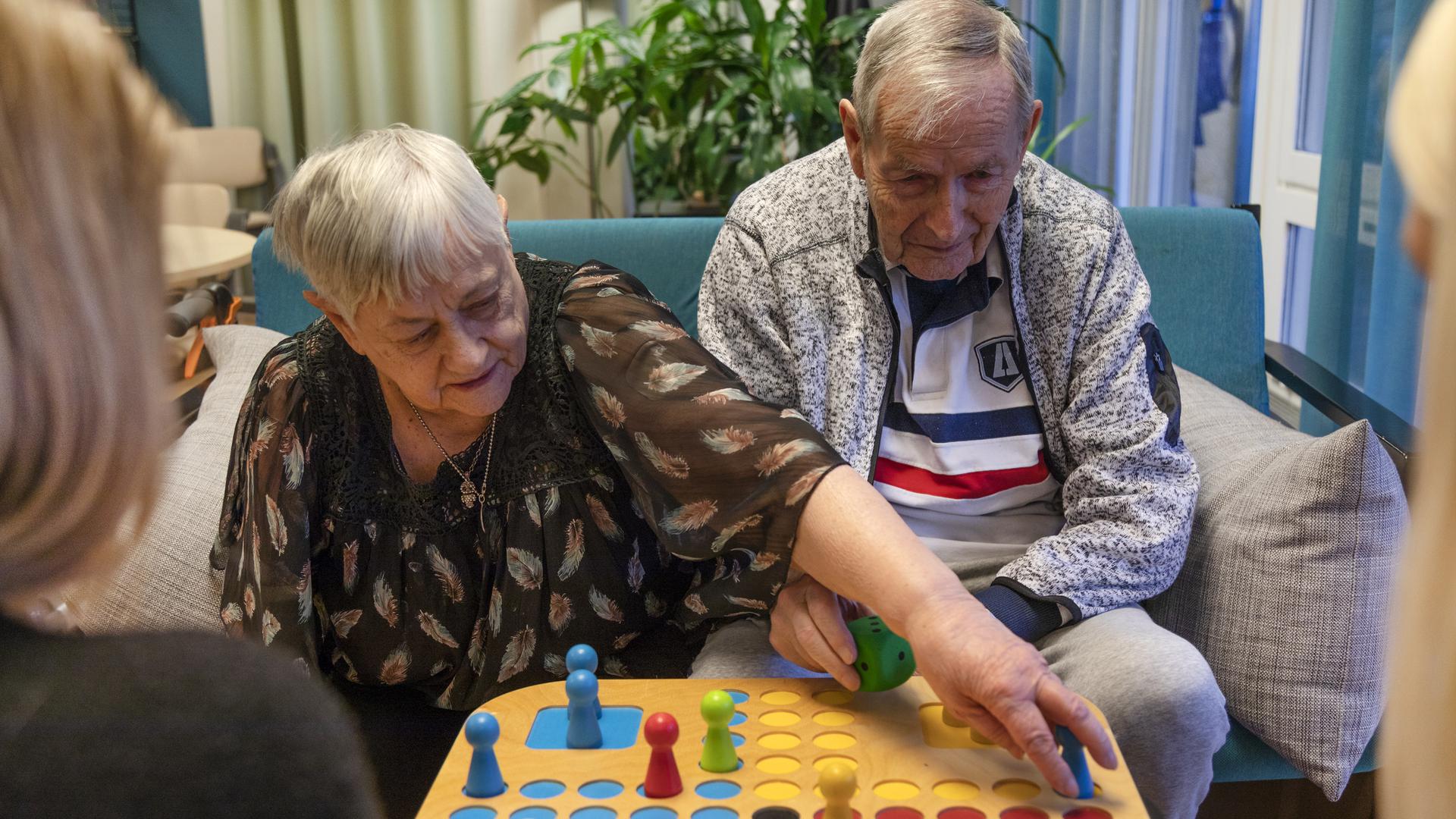 Äldre dam och herre spelar Fia med knuff ihop med personalen på äldreboendet