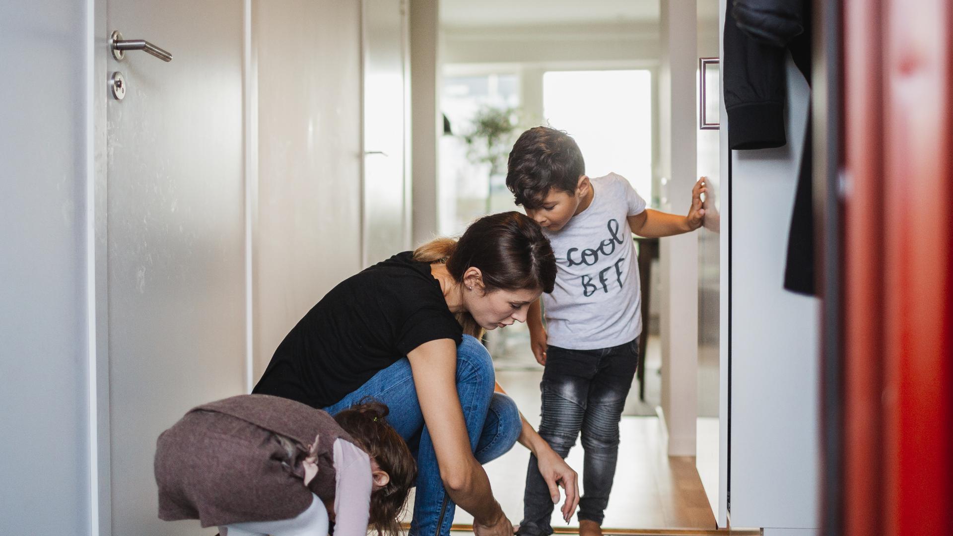 Mamma som hjälper sina barn på med skorna