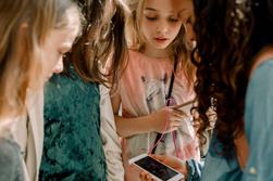 Fyra flickor i 10-årsåldern som tittar på en mobiltelefon.