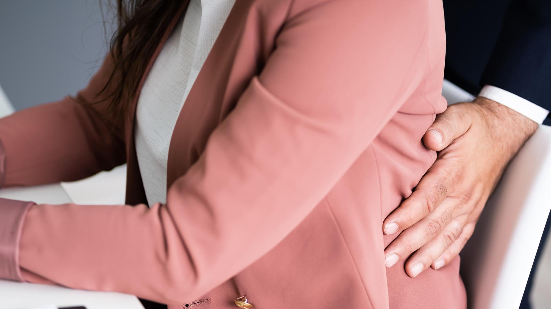 A male colleague touching a female colleague's back