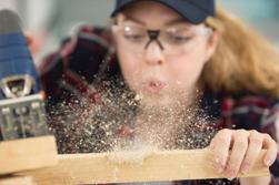 Kvinnlig snickare som blåser bort trädamm från en planka