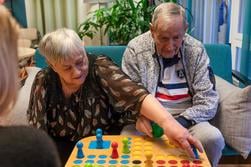 Äldre dam och herre spelar Fia med knuff ihop med personalen på äldreboendet