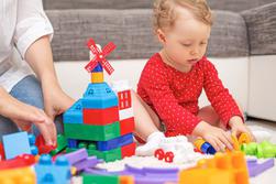 Ett litet barn som leker med legoklossar med sin mamma hemma.