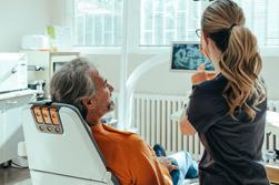Kvinnlig tandläkare som förklarar röntgenbild för en manlig patient