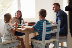 Barnfamilj som äter tillsammans i köket.