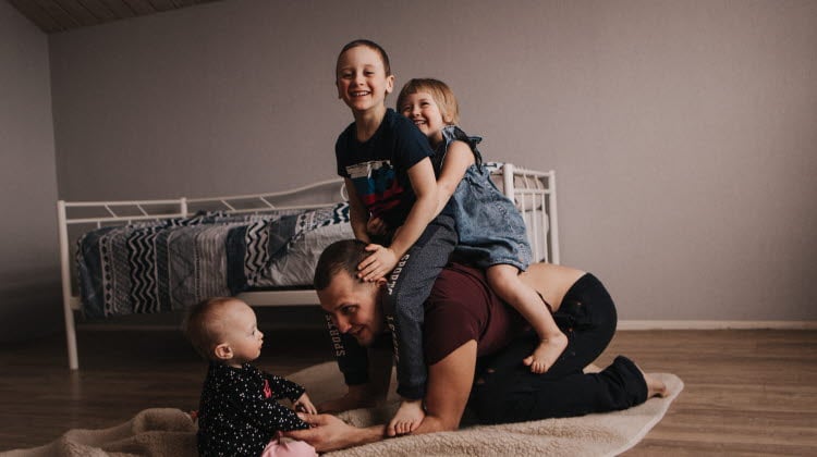 Man som leker med tre barn. Pappa som leker med sina tre barn.