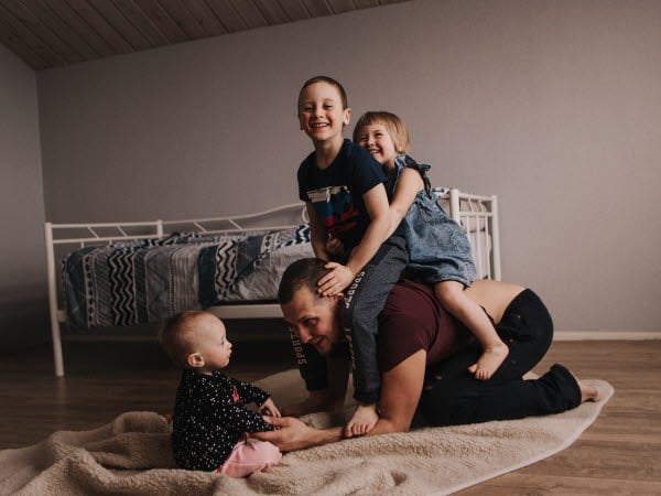 Man som leker med tre barn. Pappa som leker med sina tre barn.