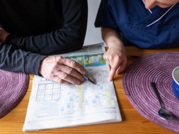 Kvinnlig hemtjänstpersonal hemma hos äldre man