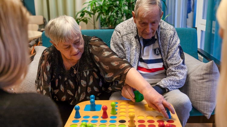 Äldre dam och herre spelar Fia med knuff ihop med personalen på äldreboendet