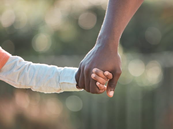 Barn och förälder som håller varandra i handen