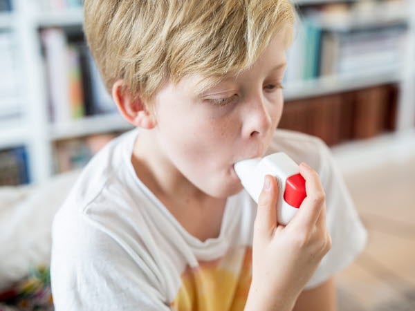 Pojke som inhalerar astmaspray