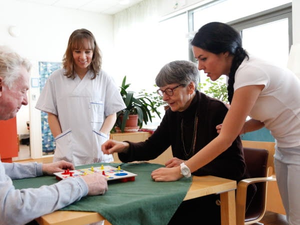 Äldre par som spelar Fia med knuff på ett äldreboende. 