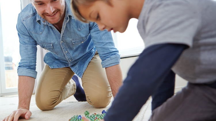 Far och son som spelar kula inomhus