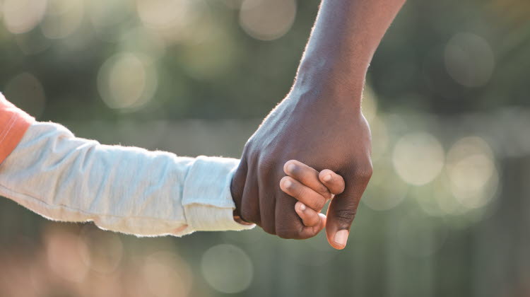 Barn och förälder som håller varandra i handen