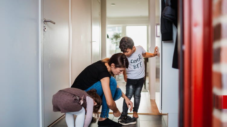 Mamma som hjälper sina barn på med skorna