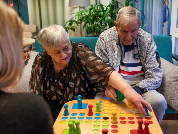 Äldre dam och herre spelar Fia med knuff ihop med personalen på äldreboendet