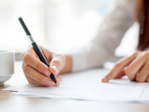 Kvinna håller penna medan hon läser ett dokument