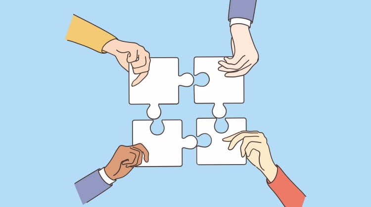 Fyra händer som håller ihop varsin pusselbit