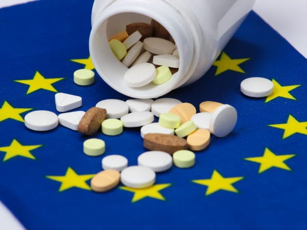 En medicinburk och olika tabletter som ligger på en EU-flagga.